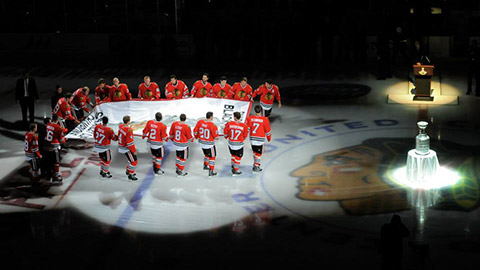 Hráči Blackhawks s vlajkou pro vítěze Stanley Cupu 2013