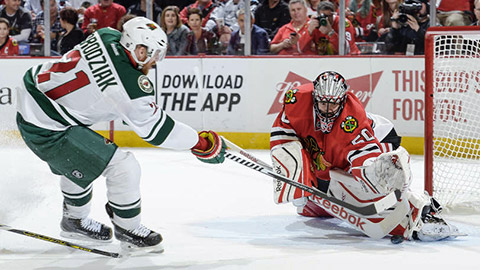 Corey Crawford zasahuje při brejku Kyla Brodziaka