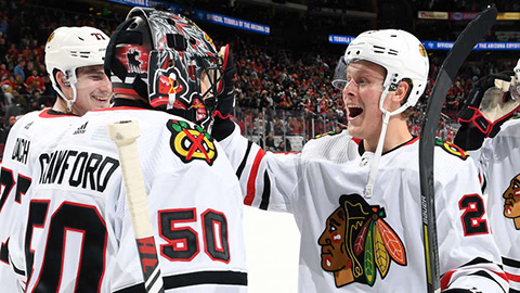 Corey Crawford a Adam Boqvist slaví výhru (© Norm Hall/NHLI via Getty Images)